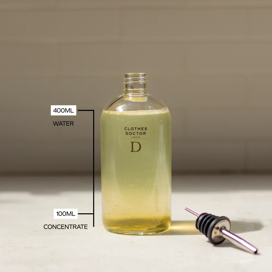 Bottle of 'Clothes Doctor' laundry solution with a dropper on a neutral background