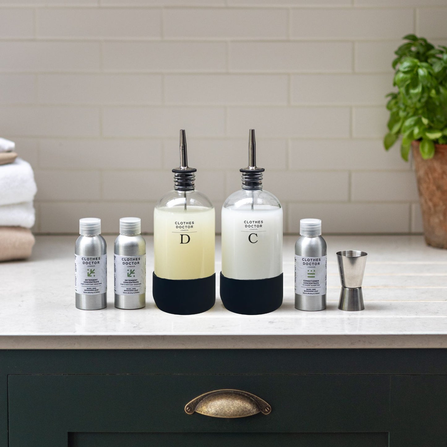 Set of bottles and containers on a kitchen counter with a plant in the background