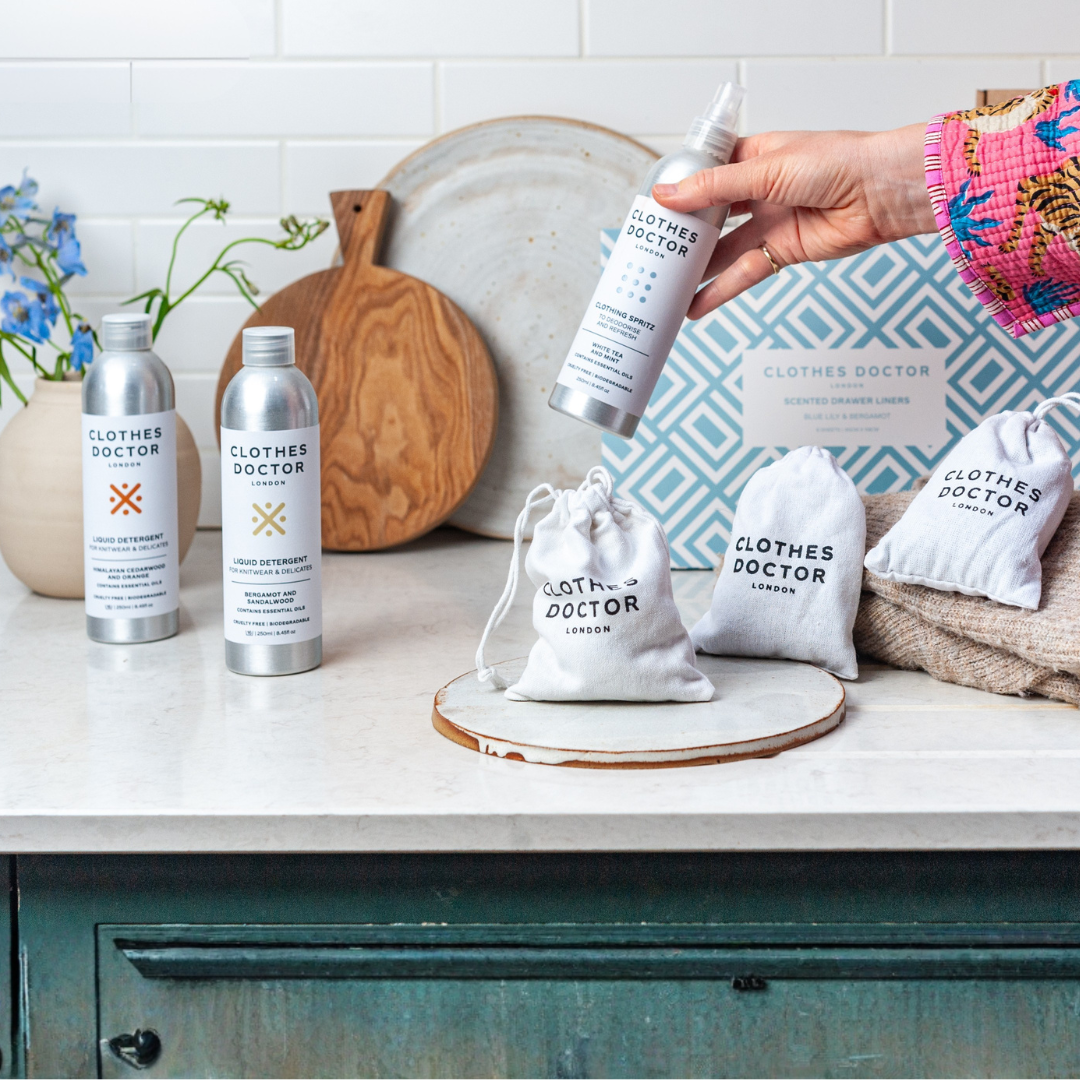 Clothes Doctor products on a kitchen counter with a hand holding a spray bottle.