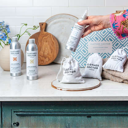 Clothes Doctor products on a kitchen counter with a hand holding a spray bottle.
